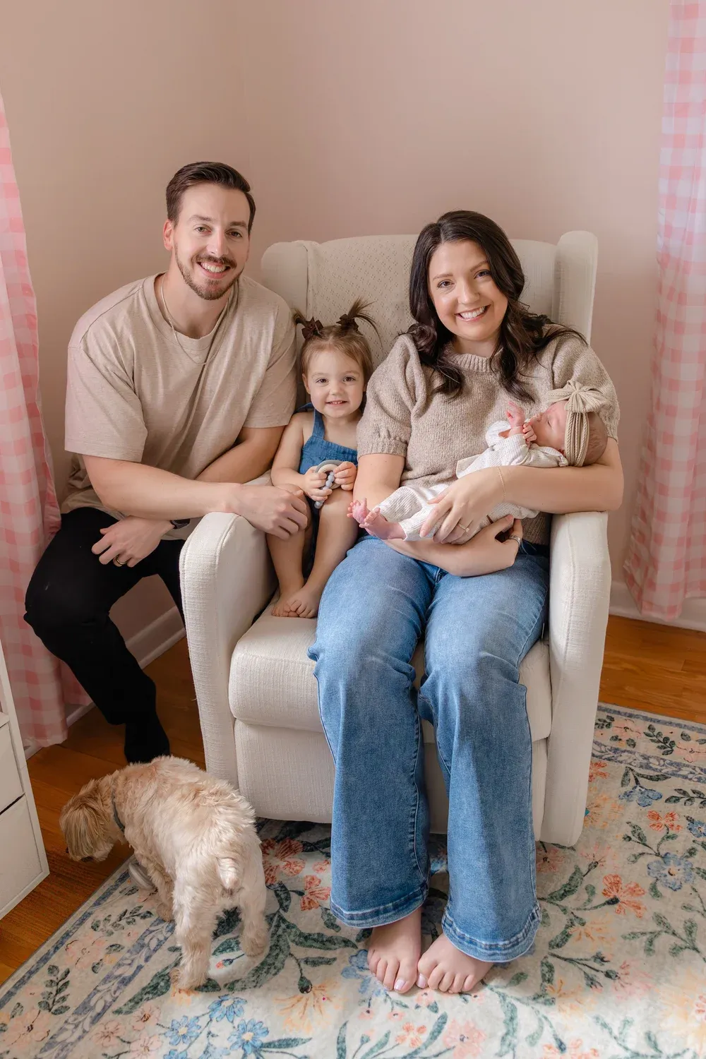 Parents with their toddler, newborn, and dog on a couch at home