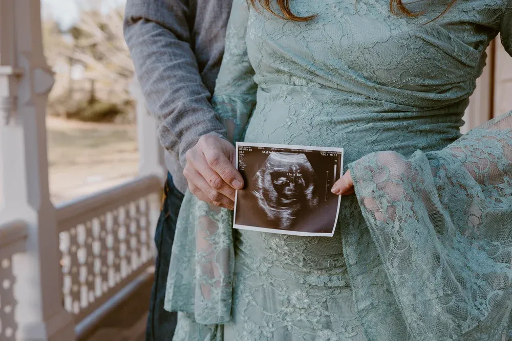 Couple holding an ultrasound photo announcing they're having a boy