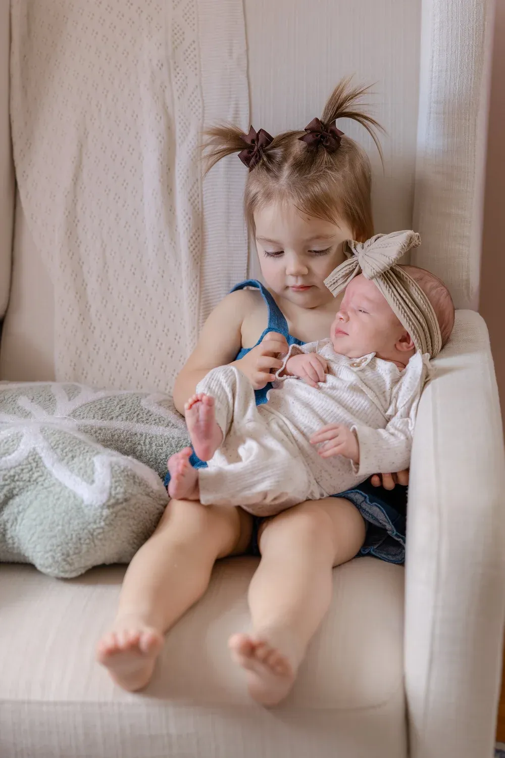 Big sister holding her newborn sibling on a couch