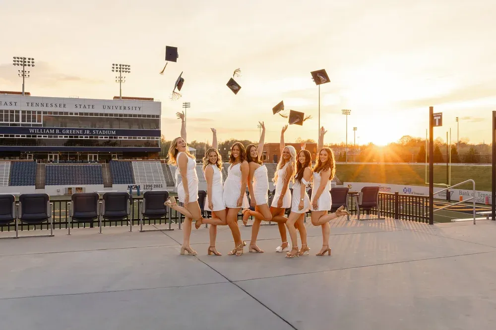 Line of graduates tossing their caps at golden hour